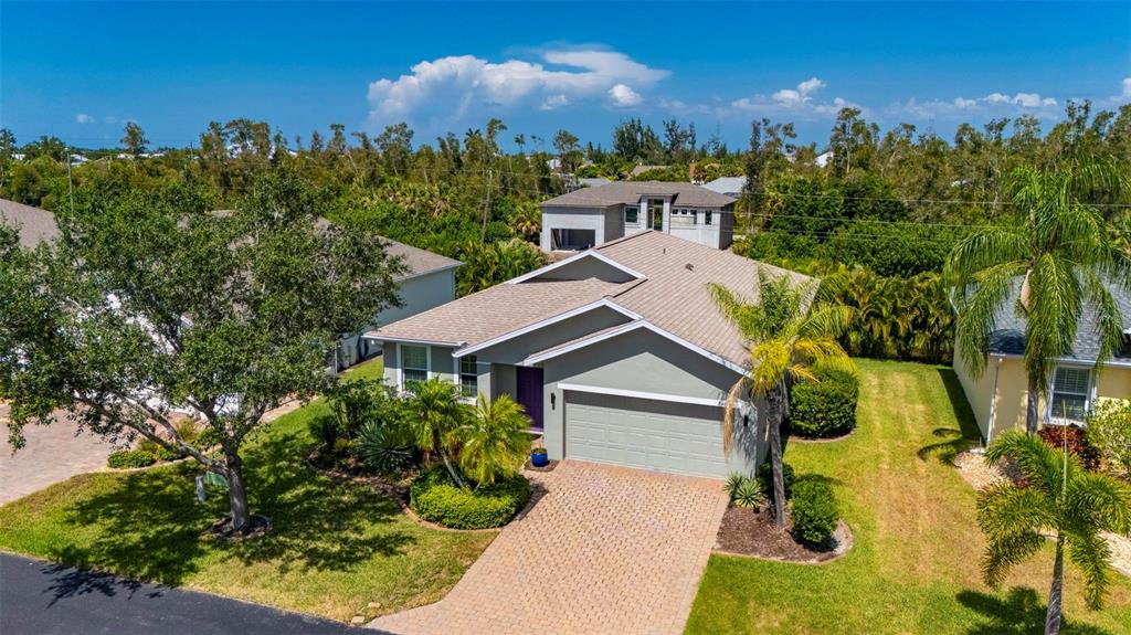 An aerial view shows a single-story gray house with a paved driveway and palm trees — 24604 RIO VILLA LAKES CIRCLE, PUNTA GORDA, FL