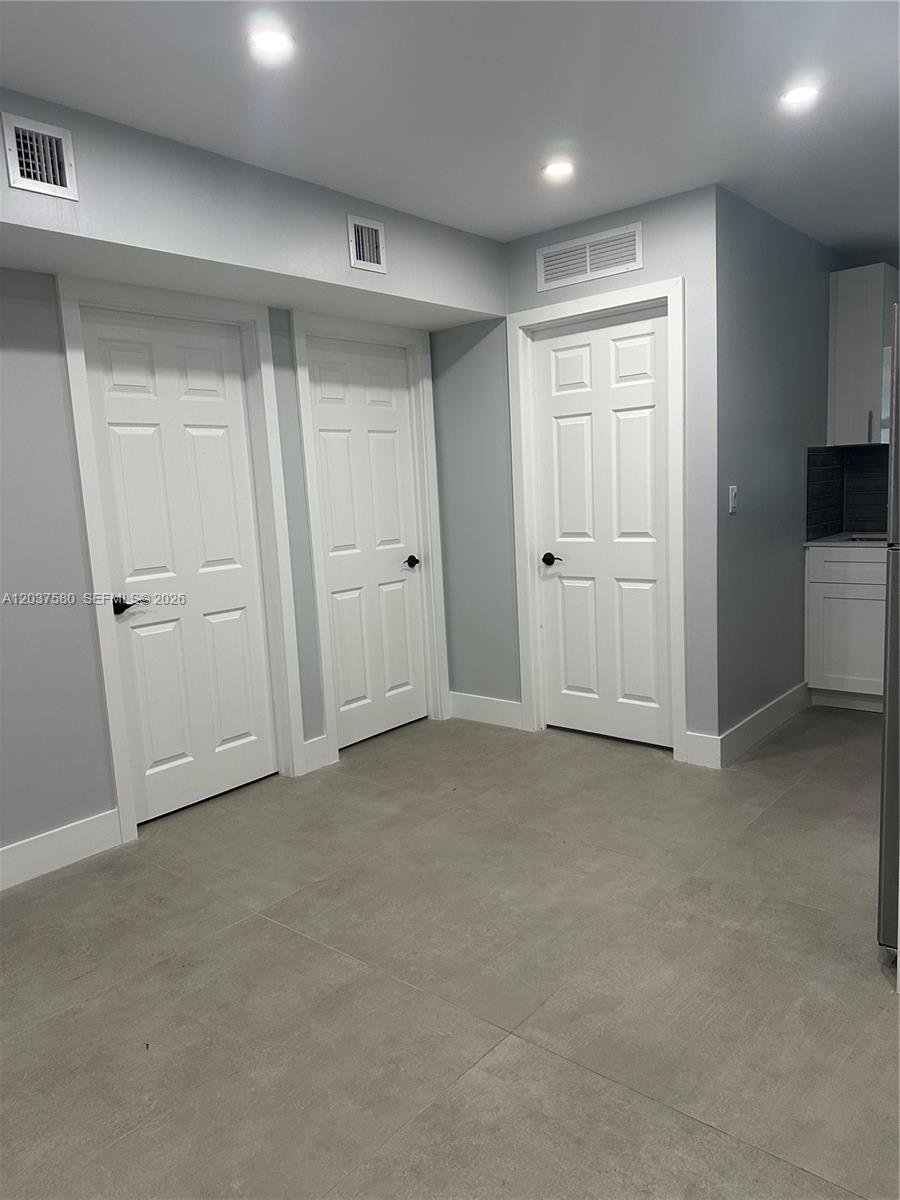 A room with gray tile flooring, three white doors, and recessed ceiling lighting — 1628 NW 15th St # A, Miami FL 33125, MIAMI, FL