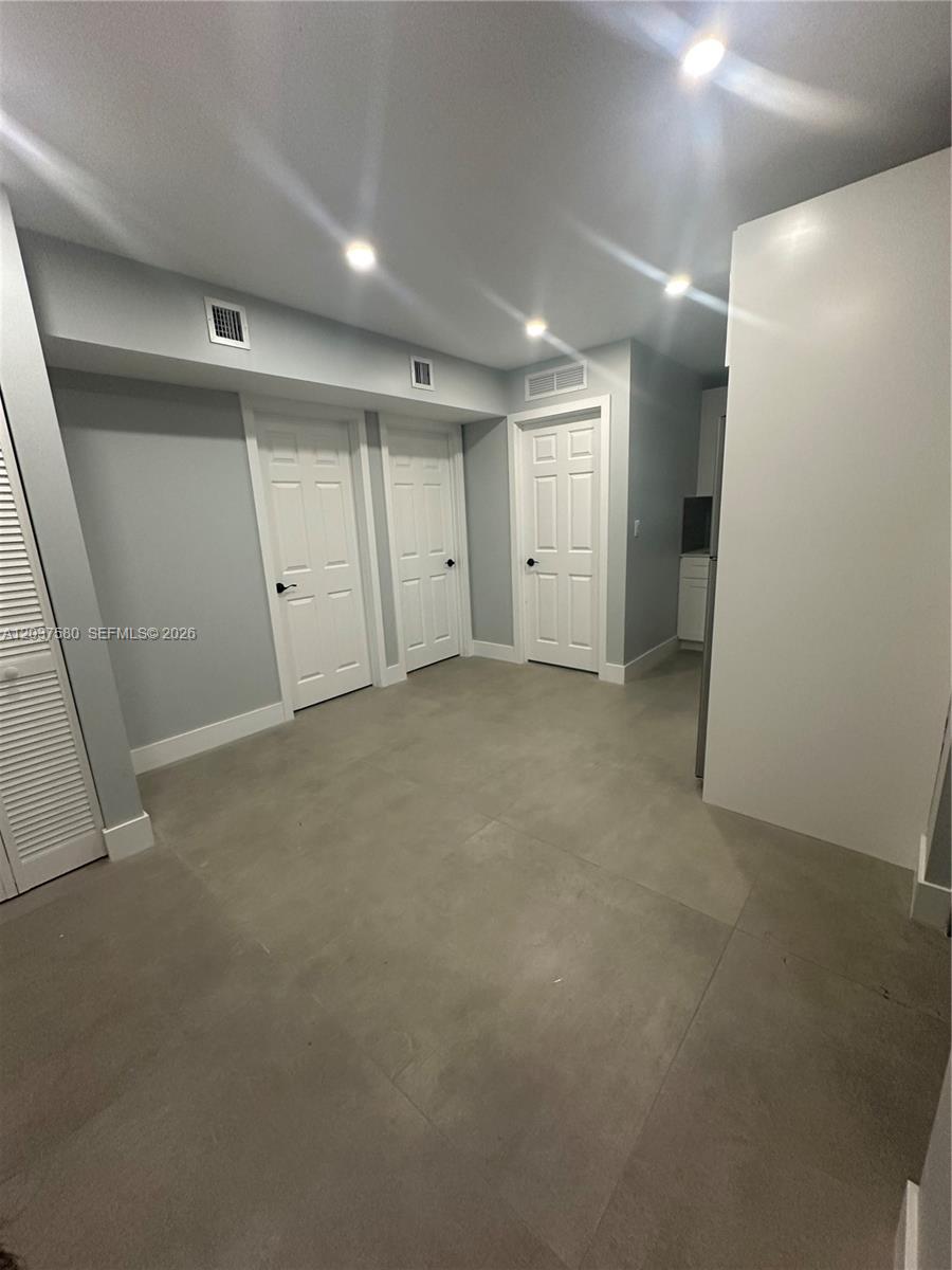 A room with gray tile flooring, white walls, and three white interior doors — 1628 NW 15th St # A, Miami FL 33125, MIAMI, FL
