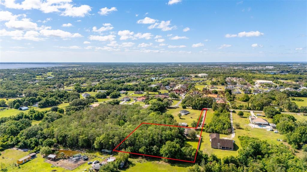 An aerial view shows a wooded lot outlined in red within a residential area — 2507 WINNERS CIRCLE, KISSIMMEE, FL