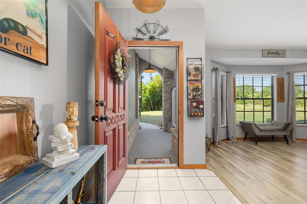 An entryway with a red door opens to a covered porch and a living area — 2507 WINNERS CIRCLE, KISSIMMEE, FL