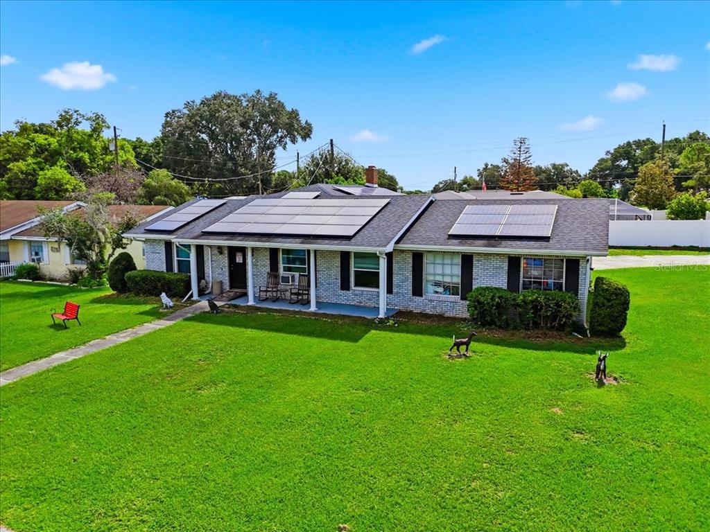 An exterior view of a single-story brick house with solar panels on the roof — 408 LANIER LANE, WINTER HAVEN, FL