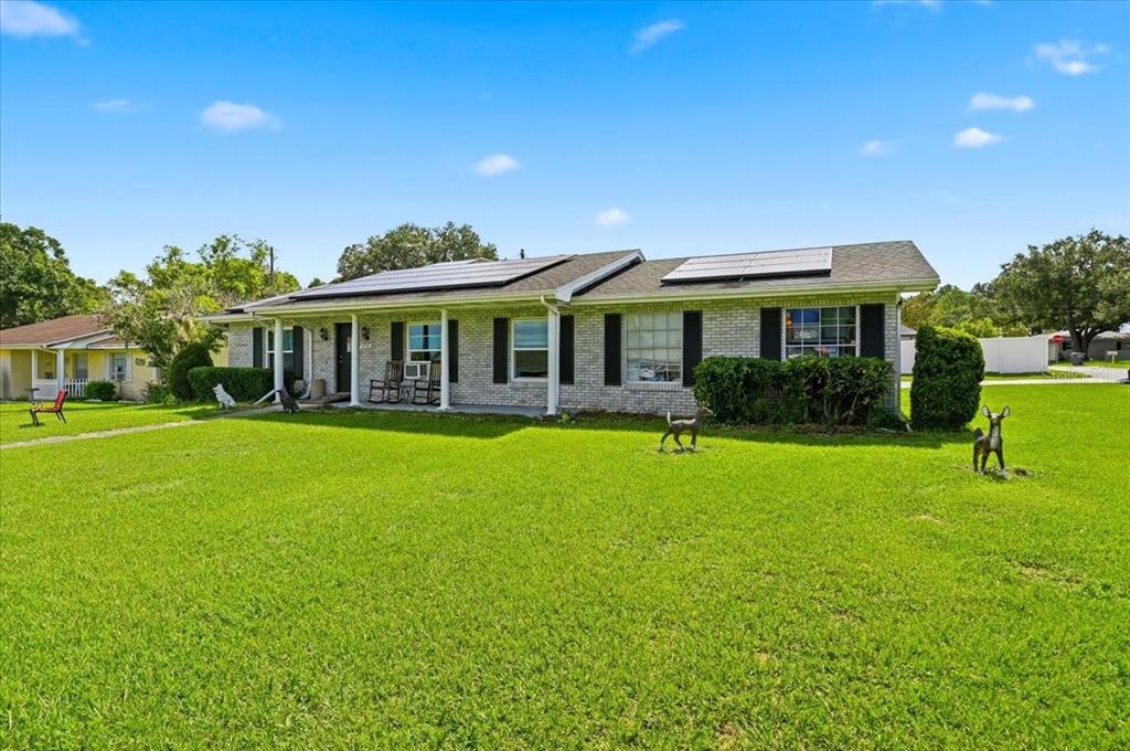 A single-story brick house with solar panels on the roof and a large front lawn — 408 LANIER LANE, WINTER HAVEN, FL