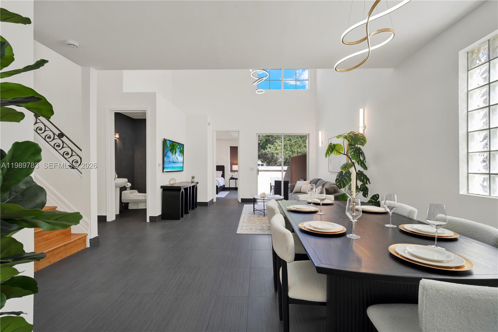 A modern dining area features a dark wood table, tile flooring, and high ceilings — 1251 Hayes St, Hollywood FL 33019, HOLLYWOOD, FL