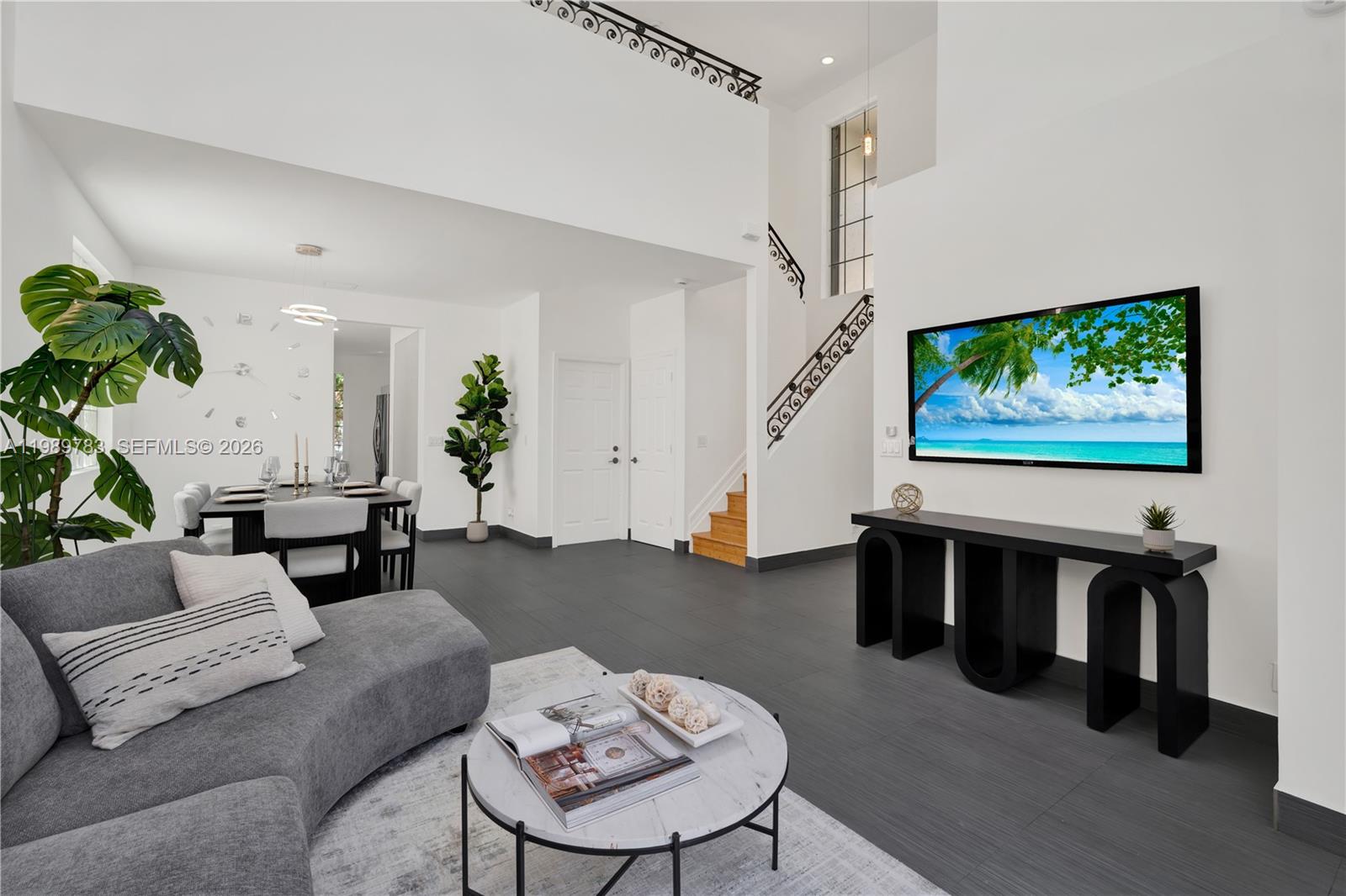 A modern living room features dark tile floors, a gray sectional, and a wall-mounted television — 1251 Hayes St, Hollywood FL 33019, HOLLYWOOD, FL