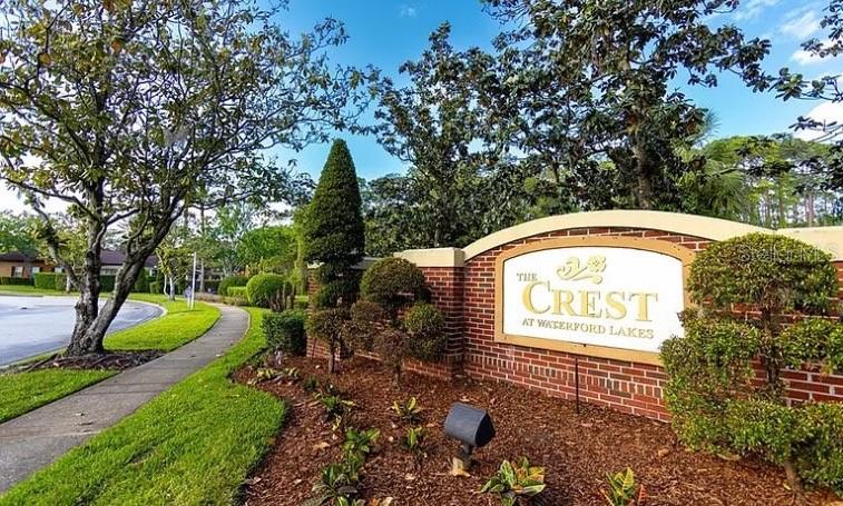 A brick monument sign for The Crest at Waterford Lakes stands near a sidewalk and trees — 738 CREST PINES DRIVE UNIT 728, ORLANDO, FL