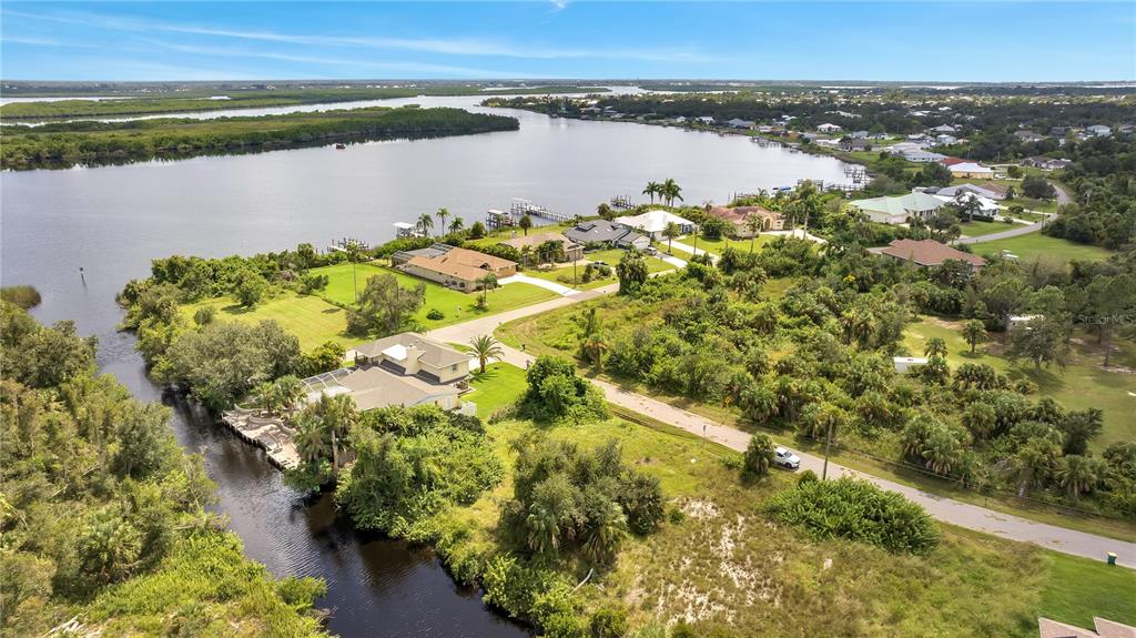 An aerial view shows waterfront homes along a canal leading into a large bay — 27438 SAN MARCO DRIVE, PUNTA GORDA, FL