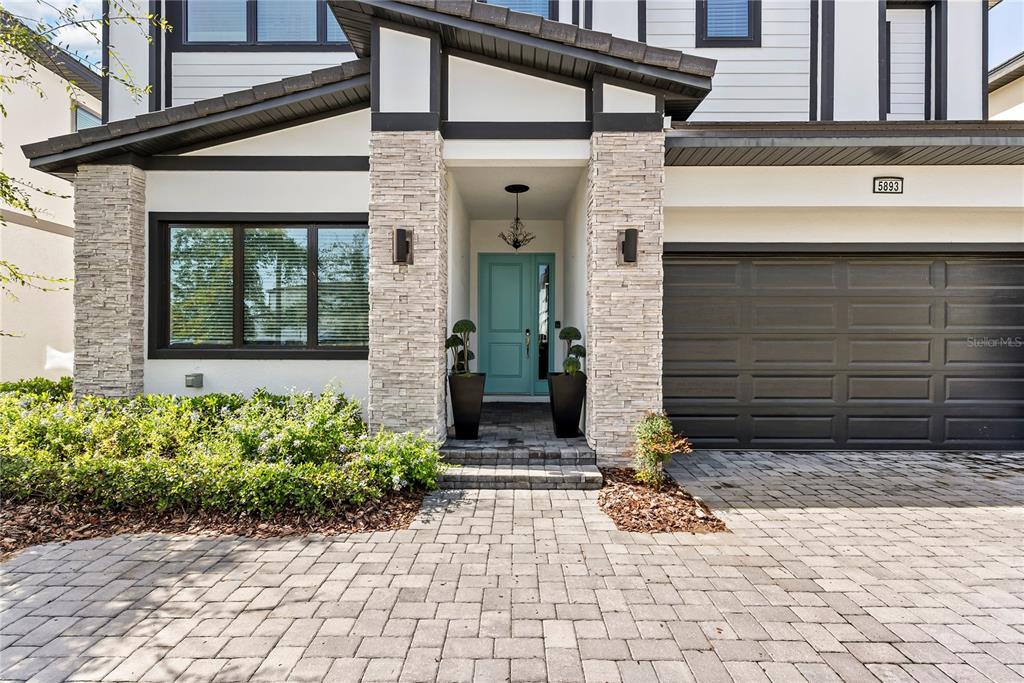 The exterior of a two-story house features a stone-accented entryway and a paved driveway — 5893 HIGH SEAS DRIVE, ORLANDO, FL