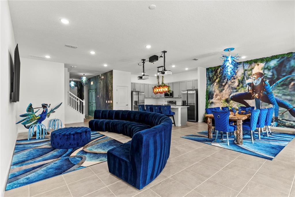 An open-concept living and dining area features Avatar-themed decor, blue velvet furniture, and tile flooring — 5893 HIGH SEAS DRIVE, ORLANDO, FL