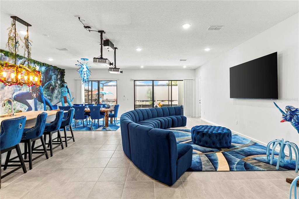 A living and dining area features blue velvet furniture, Avatar-themed decor, and a large television — 5893 HIGH SEAS DRIVE, ORLANDO, FL