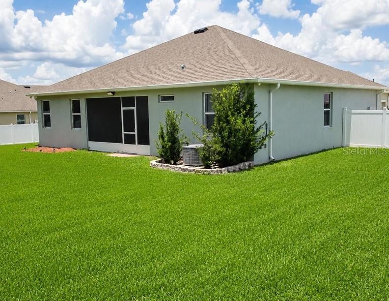 The exterior rear view of a single-story house with a screened-in patio and lawn — 1320 SE 63RD COURT ROAD, OCALA, FL