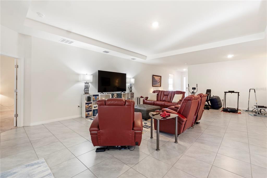 A spacious living room features red leather furniture, tile flooring, and a wall-mounted television — 1320 SE 63RD COURT ROAD, OCALA, FL