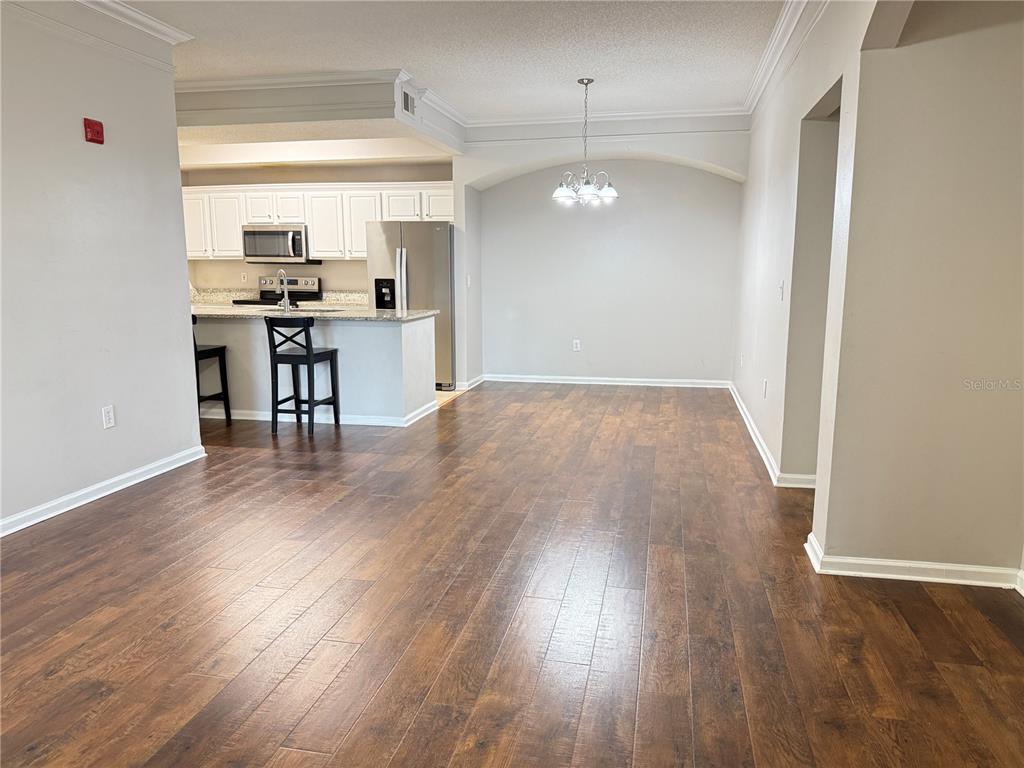 An open-concept dining area and kitchen with wood-look flooring and white cabinetry — 12017 VILLANOVA DRIVE UNIT 109, ORLANDO, FL