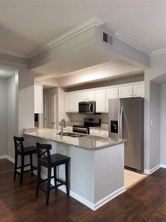 A kitchen features white cabinets, granite countertops, stainless steel appliances, and a breakfast bar — 12017 VILLANOVA DRIVE UNIT 109, ORLANDO, FL