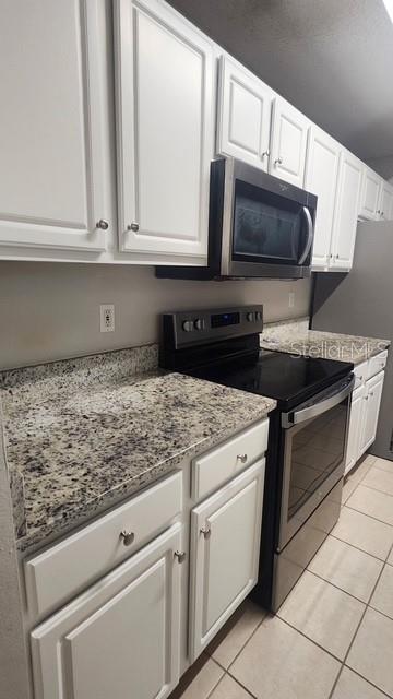 A kitchen featuring white cabinets, granite countertops, and stainless steel appliances — 12017 VILLANOVA DRIVE UNIT 109, ORLANDO, FL