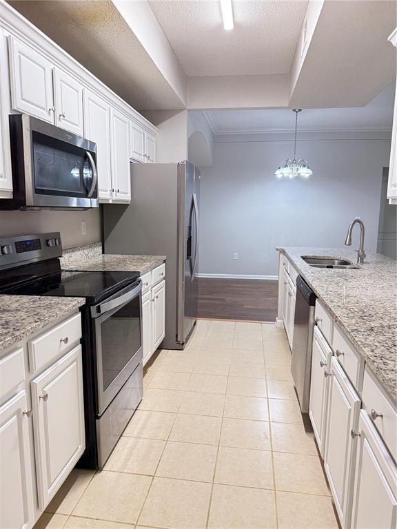 A kitchen features white cabinets, granite countertops, stainless steel appliances, and tile flooring — 12017 VILLANOVA DRIVE UNIT 109, ORLANDO, FL