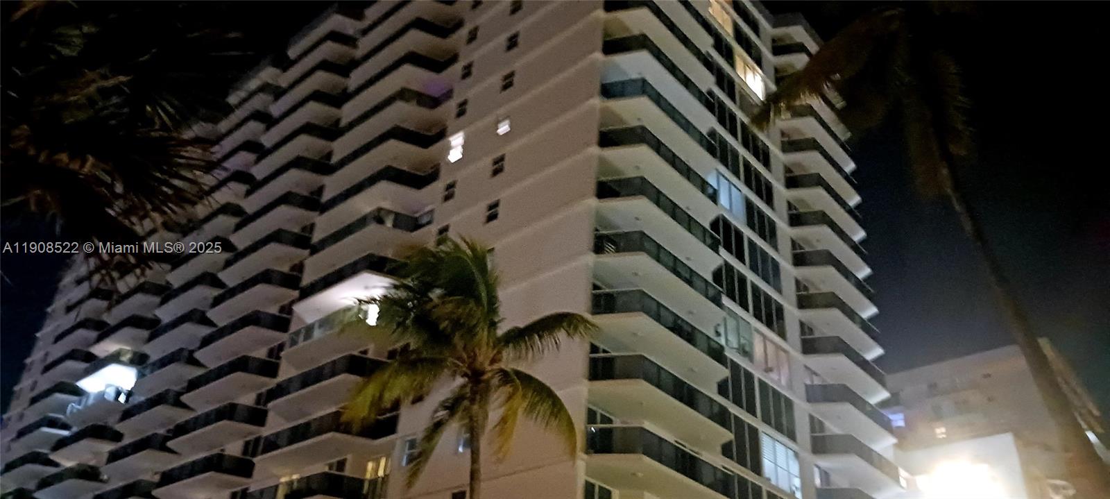 A low-angle night view of a high-rise residential building with balconies and palm trees — 2401 Collins Ave # 1708, Miami Beach FL 33140, MIAMI BEACH, FL