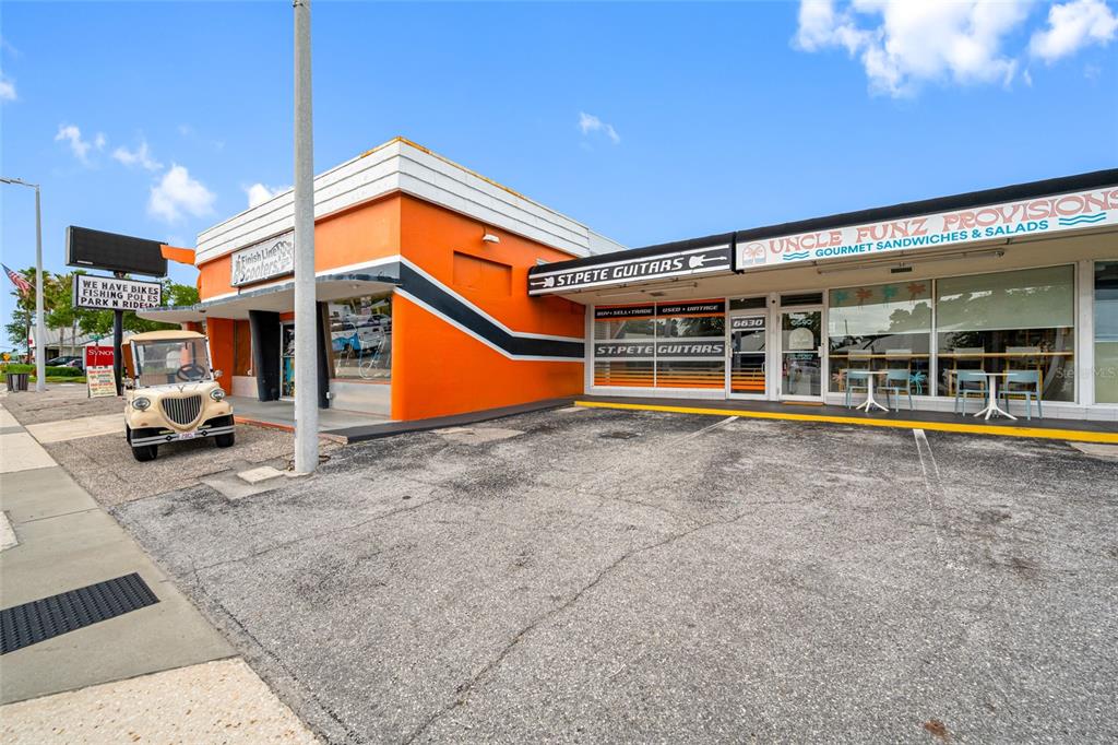 An exterior view of a commercial building with orange accents and storefronts for multiple businesses — 6630 GULF BOULEVARD, ST PETE BEACH, FL
