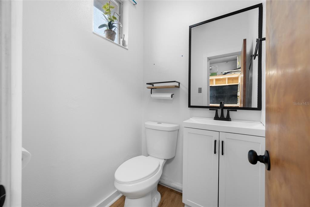 A small bathroom features a white vanity, a toilet, and a mirror with a black frame — 6630 GULF BOULEVARD, ST PETE BEACH, FL
