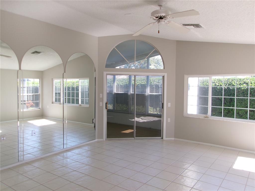A living room features light tile flooring, a mirrored wall, and a sliding glass door — 11604 VERSAILLES LANE, PORT RICHEY, FL