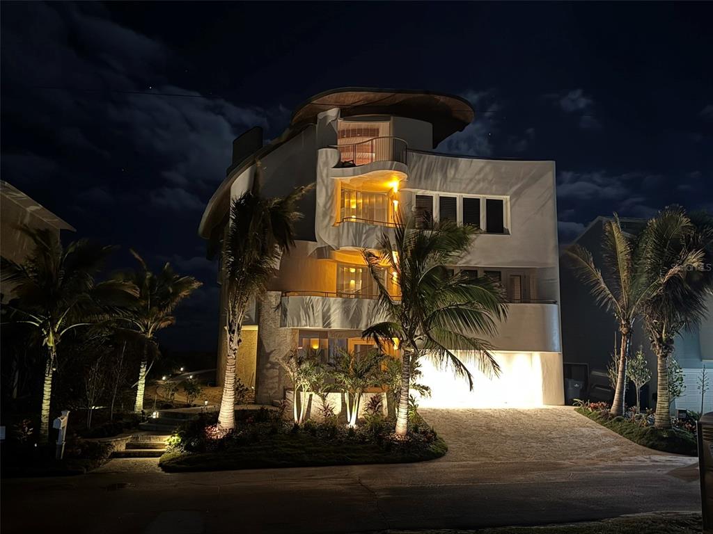 A multi-story modern home with curved balconies and exterior lighting at night — 6965 S ATLANTIC AVENUE, NEW SMYRNA BEACH, FL