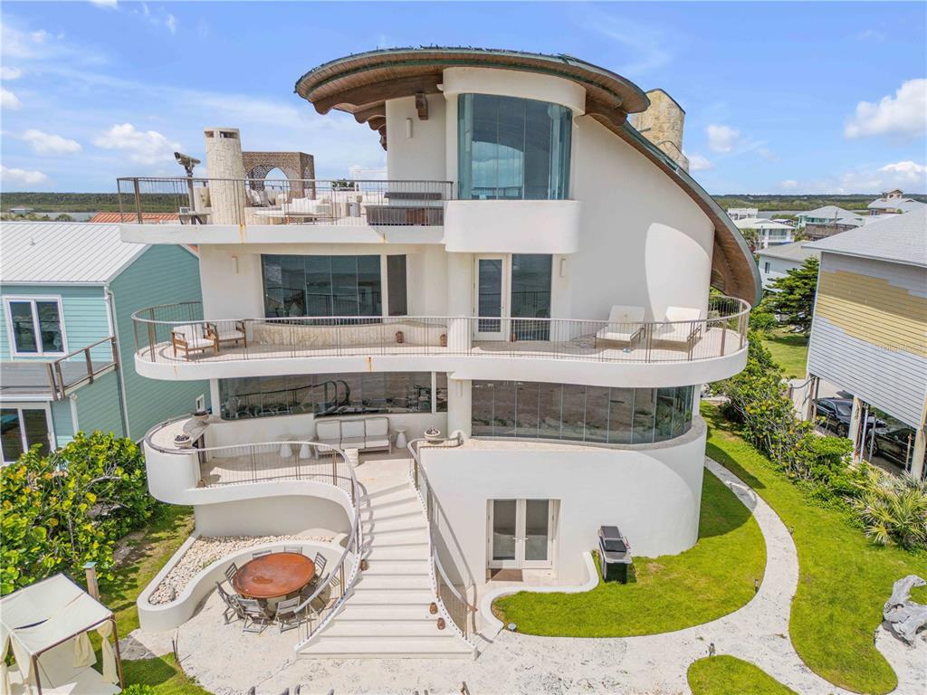 An exterior view of a multi-story, curved white house with multiple balconies and a staircase — 6965 S ATLANTIC AVENUE, NEW SMYRNA BEACH, FL