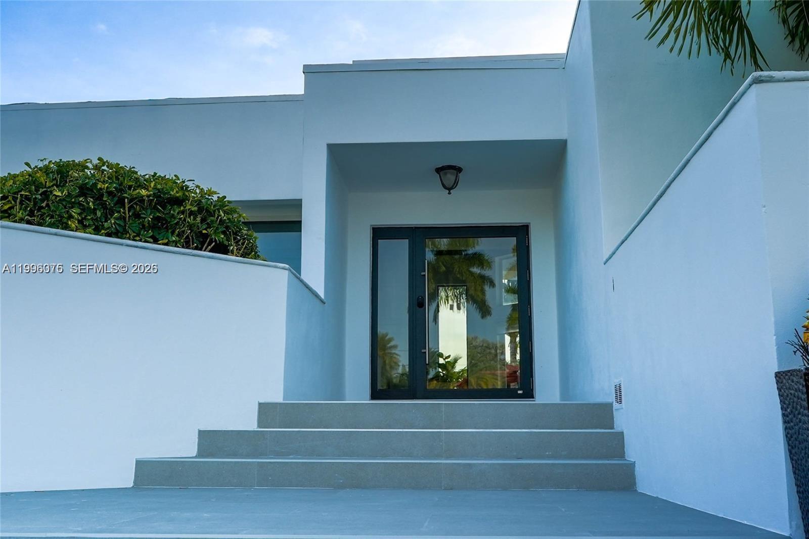 A modern white house exterior features a glass front door accessed by concrete steps — 290 NW 125th Ave, Miami FL 33182, MIAMI, FL