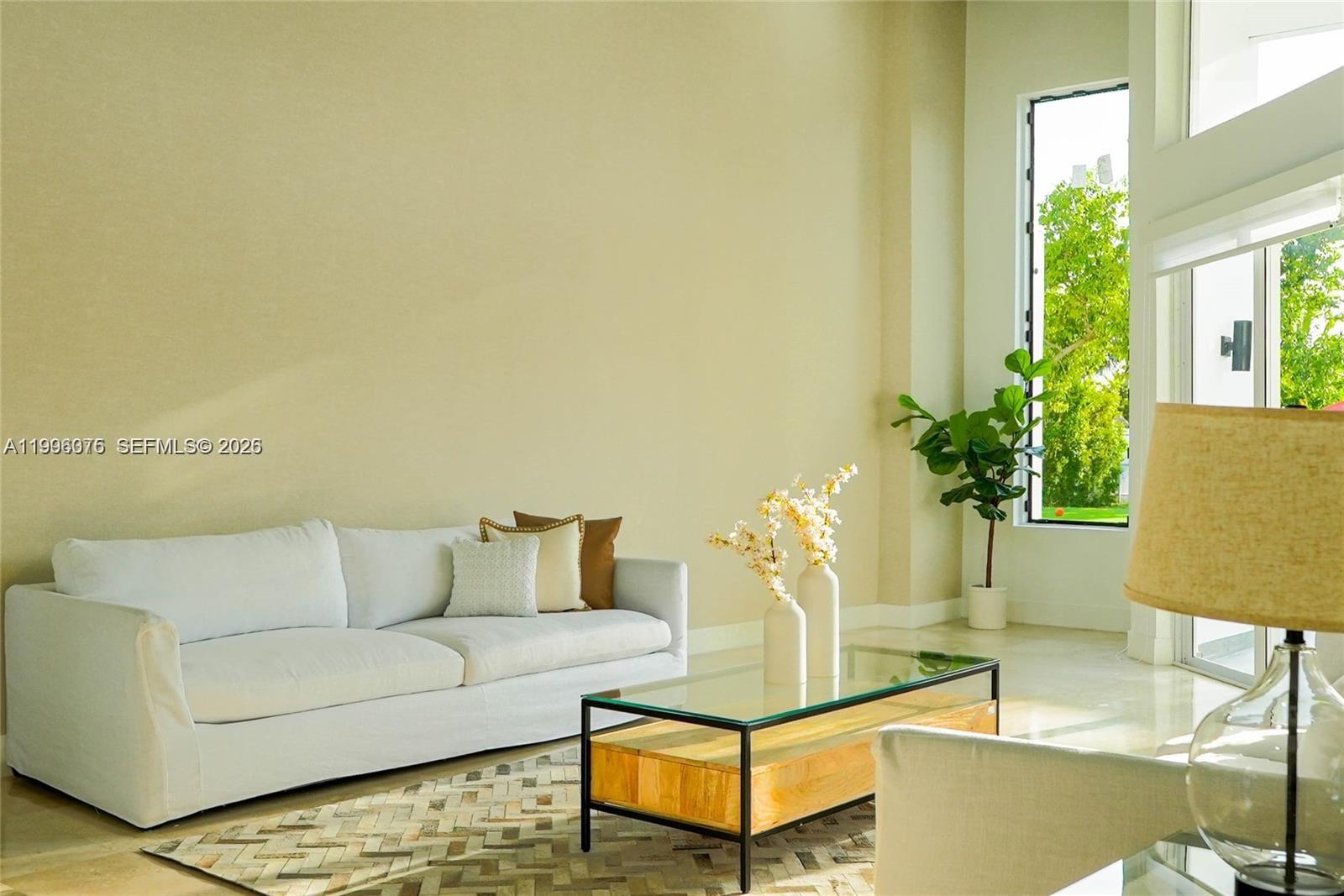 A bright living room features a white sofa, glass coffee table, and a tall window — 290 NW 125th Ave, Miami FL 33182, MIAMI, FL