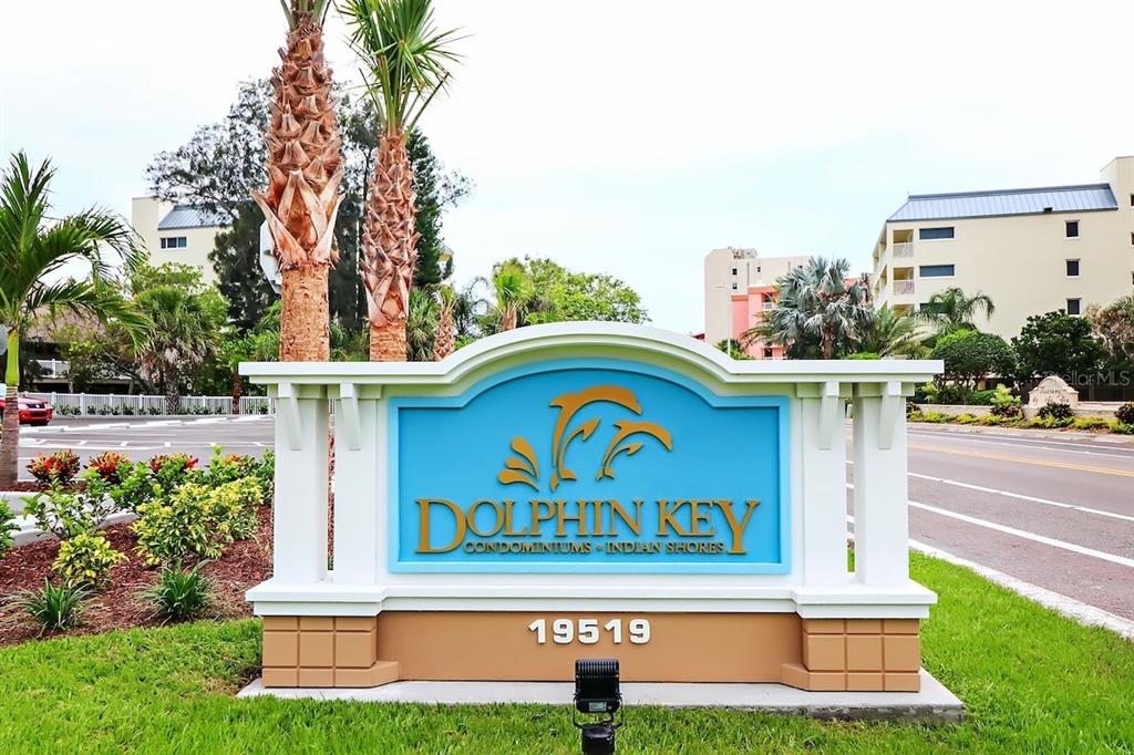 A sign for Dolphin Key Condominiums stands in front of a multi-story building — 19519 GULF BOULEVARD UNIT 206, INDIAN SHORES, FL