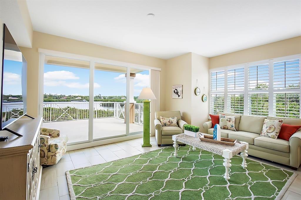A living room features a green area rug, a beige sofa, and sliding glass balcony doors — 19519 GULF BOULEVARD UNIT 206, INDIAN SHORES, FL