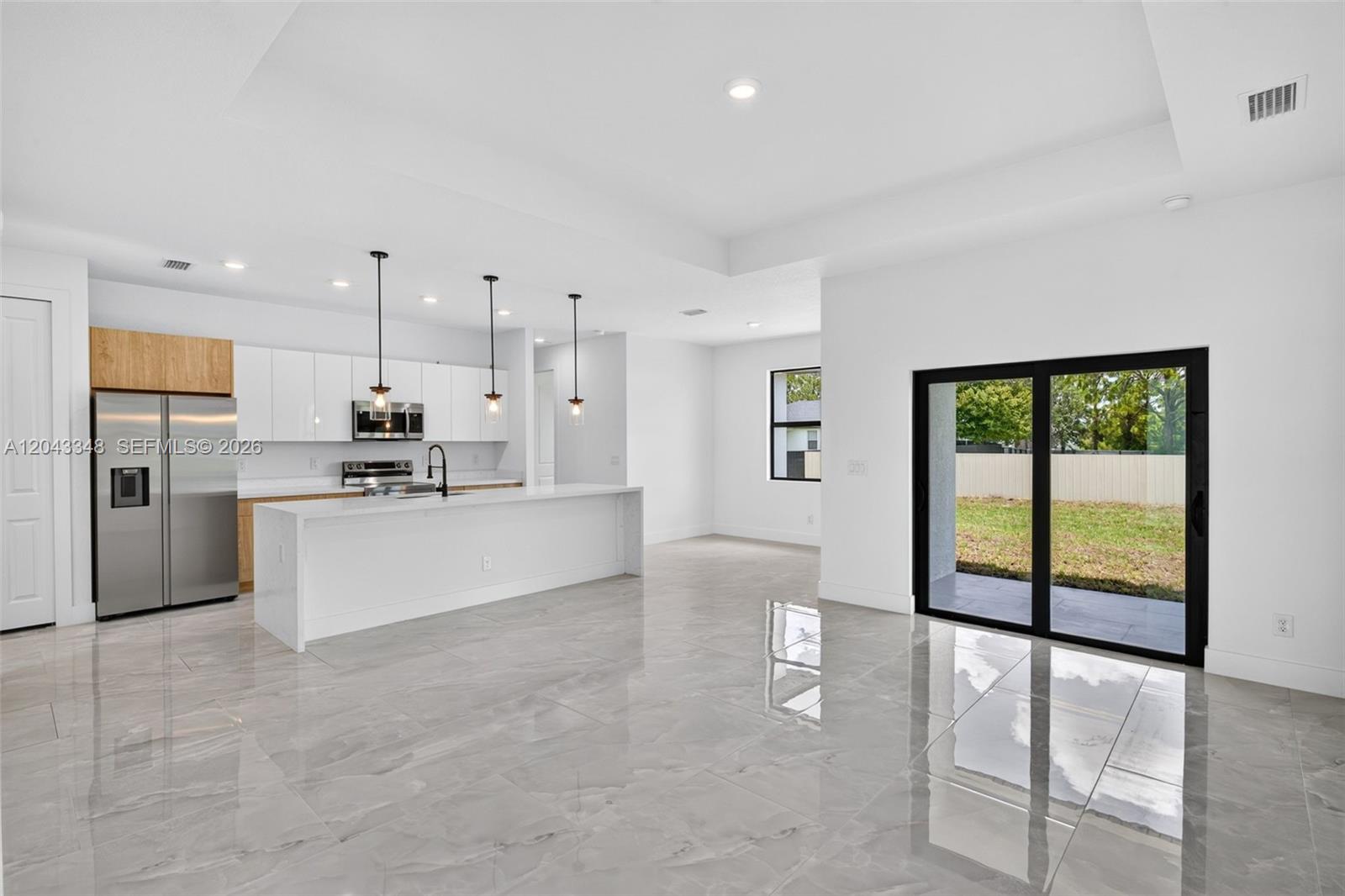 A modern kitchen features white cabinetry, a large island, and glossy tile flooring — 3216 57th st, Lehigh Acres FL 33971, LEHIGH ACRES, FL