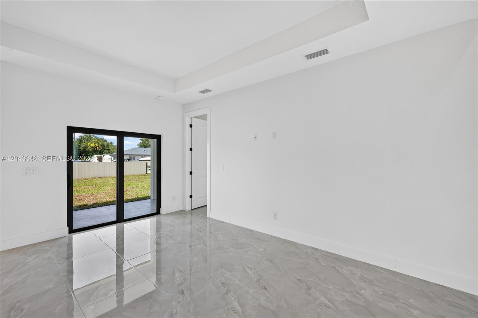 A bright room features gray marble-look tile flooring, white walls, and sliding glass patio doors — 3216 57th st, Lehigh Acres FL 33971, LEHIGH ACRES, FL