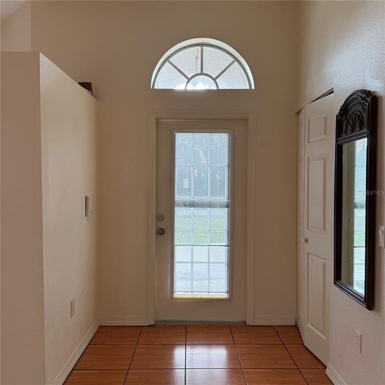 An entryway features tile flooring, a front door with a transom window, and a mirror — 239 VENETIA AVENUE, NORTH PORT, FL