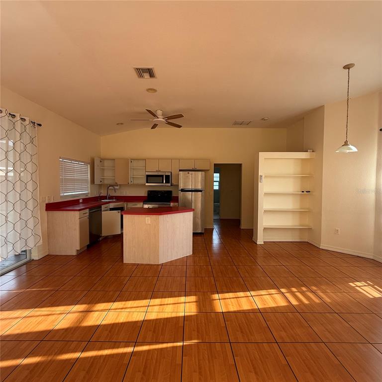 A kitchen with light wood cabinets, red countertops, and tiled floors opens to a living area — 239 VENETIA AVENUE, NORTH PORT, FL