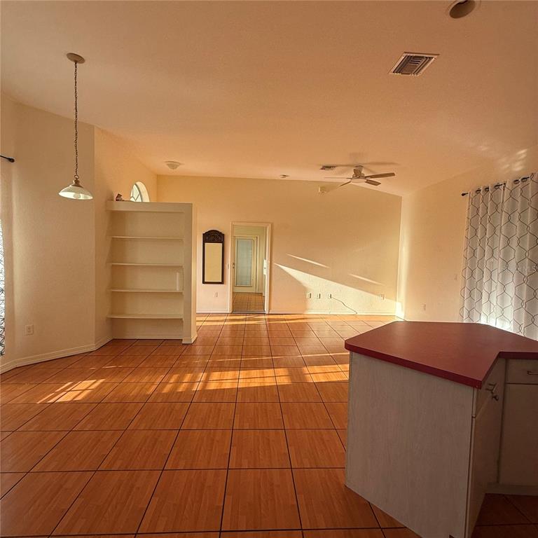 An open-concept living area features orange tile flooring, a white shelving unit, and a kitchen island — 239 VENETIA AVENUE, NORTH PORT, FL