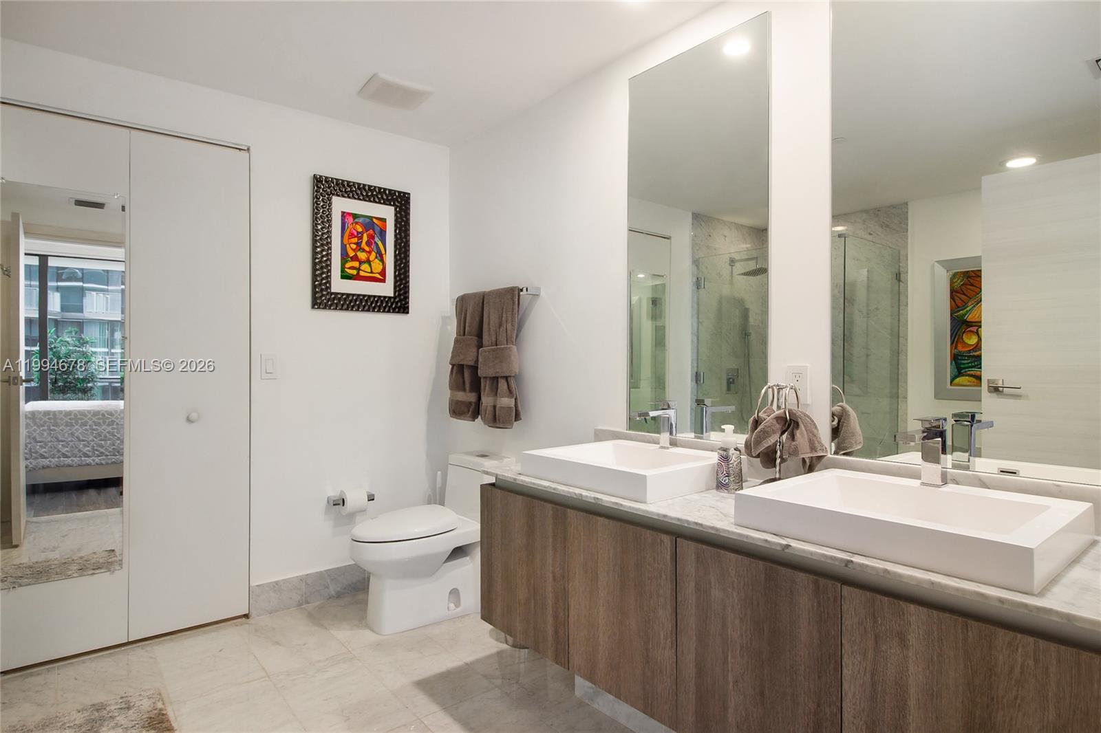 A modern bathroom features a double vanity with white sinks, marble countertops, and a toilet — 801 S Miami Ave # 2308, Miami FL 33130, MIAMI, FL