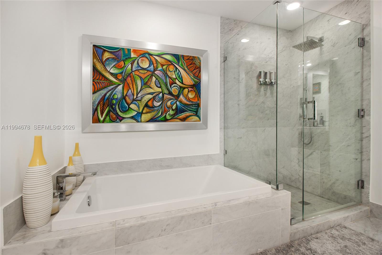 A bathroom features a white soaking tub, a glass-enclosed shower, and colorful abstract wall art — 801 S Miami Ave # 2308, Miami FL 33130, MIAMI, FL
