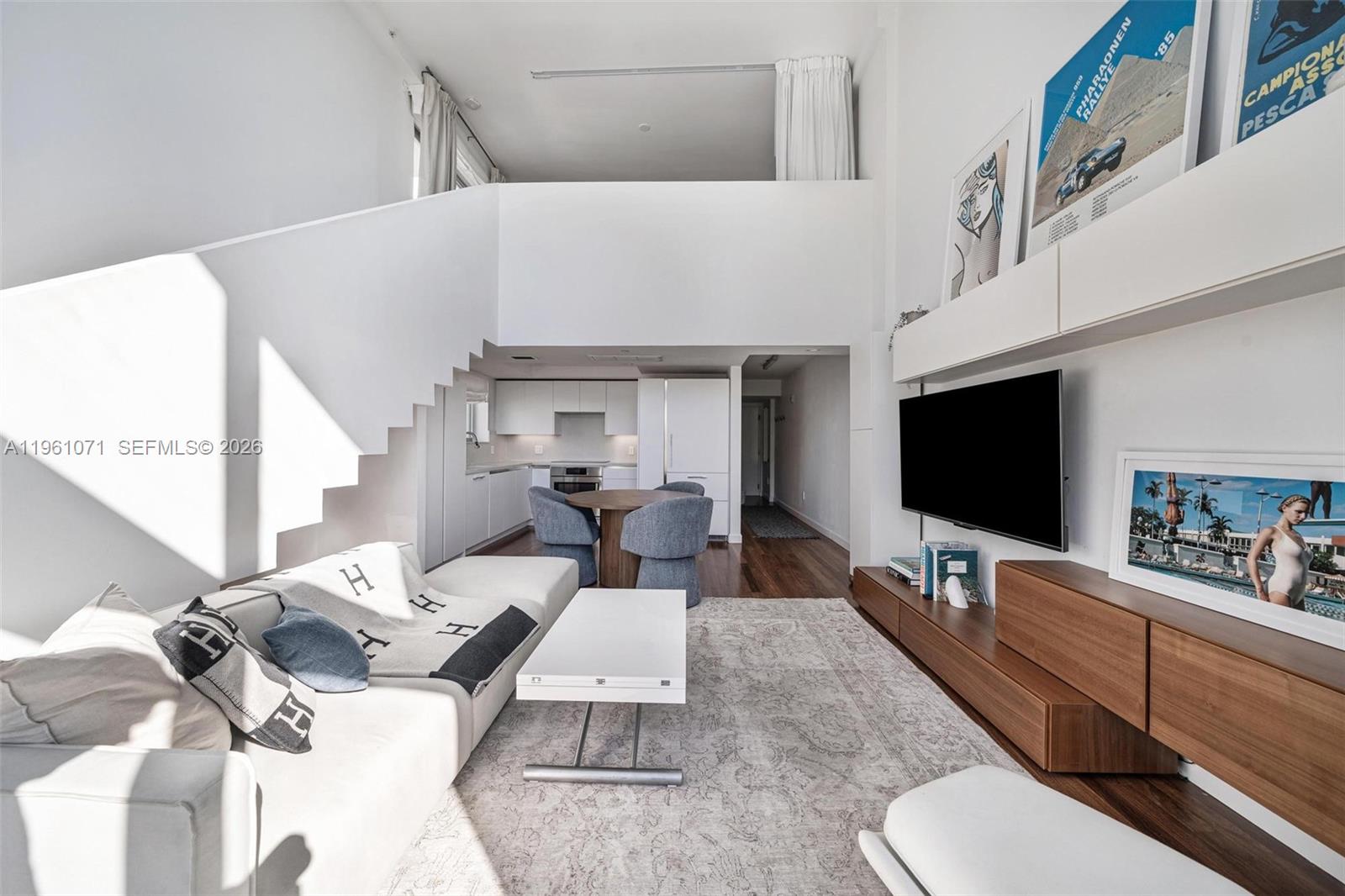 A modern living room with a lofted ceiling, white walls, and an open kitchen area — 245 Michigan Ave # 4, Miami Beach FL 33139, MIAMI BEACH, FL