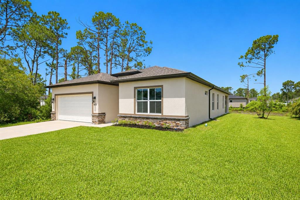 A single-story house with a beige stucco exterior, stone accents, and a two-car garage — 8211 ELKENBERRY AVENUE, NORTH PORT, FL