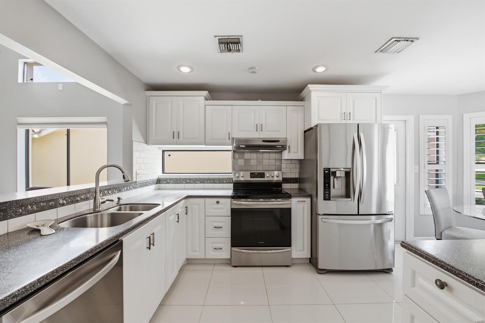 A kitchen with white cabinets, stainless steel appliances, and dark speckled countertops — 10577 Mendocino Lane, Boca Raton FL 33428, BOCA RATON, FL
