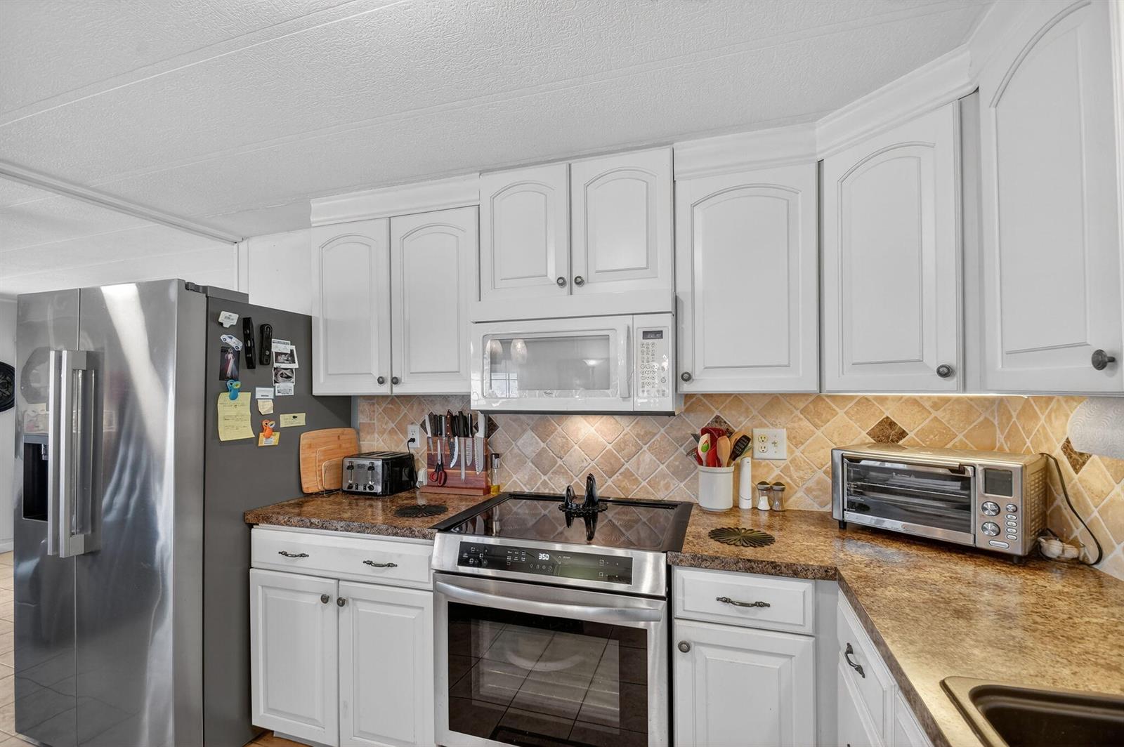 A kitchen with white cabinets, stainless steel appliances, and a brown patterned countertop — 40008 Humaco Bay, Boynton Beach FL 33436, BOYNTON BEACH, FL