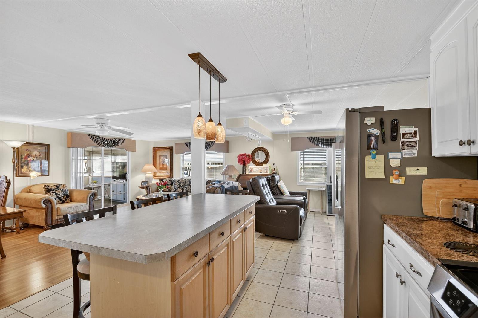 A kitchen island with a gray countertop sits in an open-concept room with tile flooring — 40008 Humaco Bay, Boynton Beach FL 33436, BOYNTON BEACH, FL