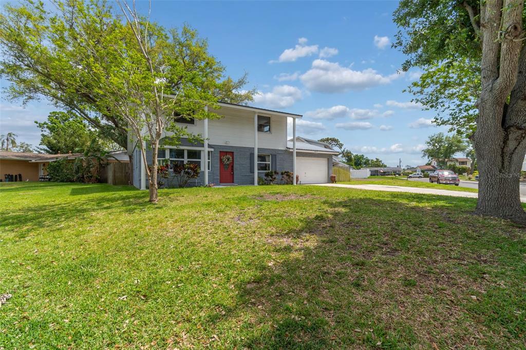 A two-story house with a grey brick lower level, white siding, and a red front door — 8043 124TH STREET, SEMINOLE, FL