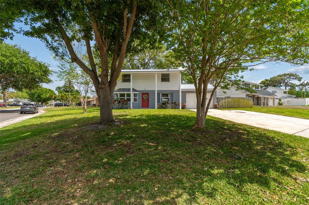 A two-story house with a white and gray exterior sits behind two large trees — 8043 124TH STREET, SEMINOLE, FL