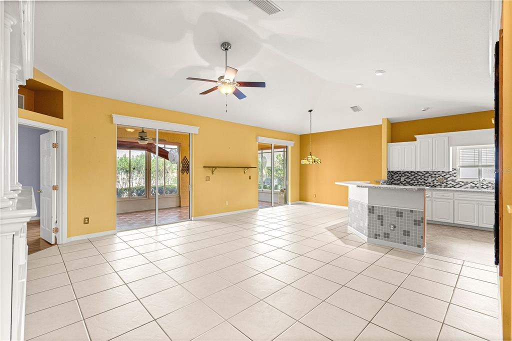 A spacious living area with yellow walls, tile flooring, a ceiling fan, and an open kitchen — 2352 NW 58TH TERRACE, OCALA, FL