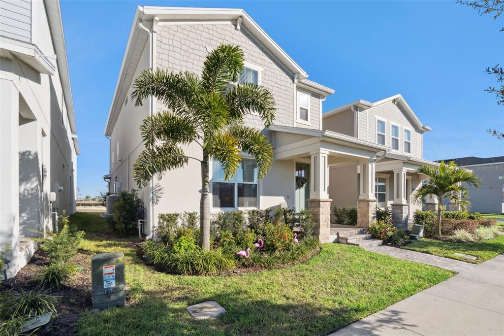 A two-story suburban house with a palm tree, stone-accented porch, and pink flamingo lawn ornaments — 13067 TOLLCROSS WAY, WINTER GARDEN, FL