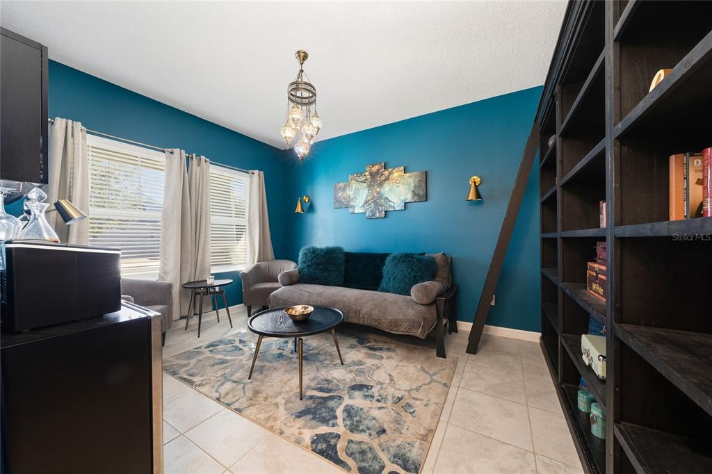 A living room features teal walls, a gray sofa, a patterned rug, and a bookshelf — 11059 LONGLEAF WOODS DRIVE, ORLANDO, FL