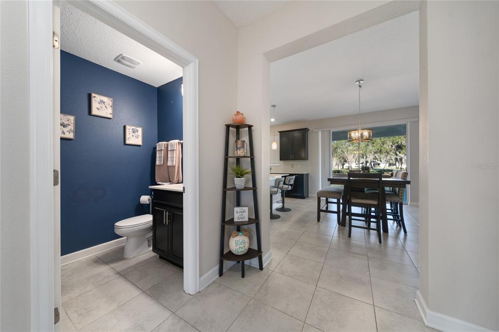 A view from a hallway into a blue-walled powder room and an open dining area — 11059 LONGLEAF WOODS DRIVE, ORLANDO, FL