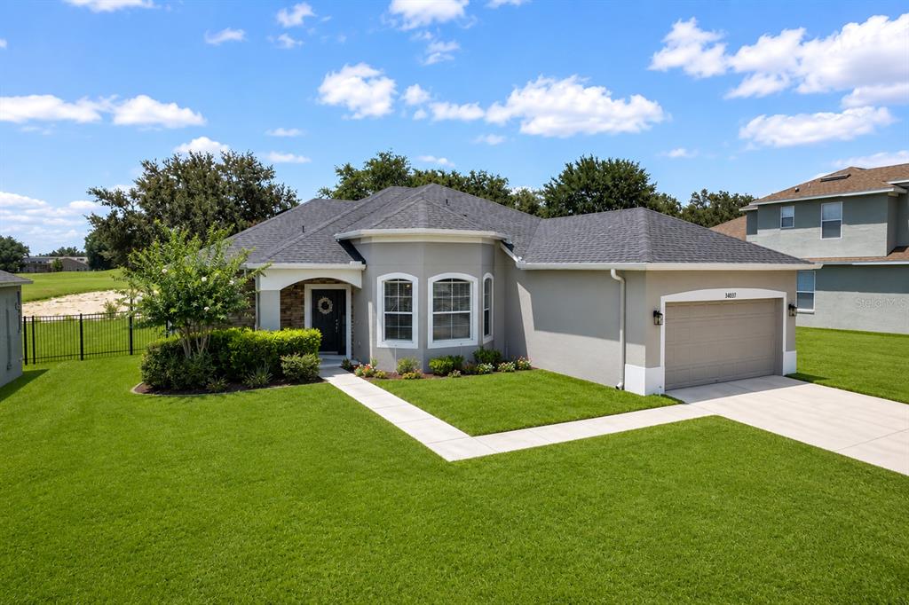 A single-story house with a gray exterior, a two-car garage, and a manicured lawn — 34037 FORTUNADO STREET, SORRENTO, FL