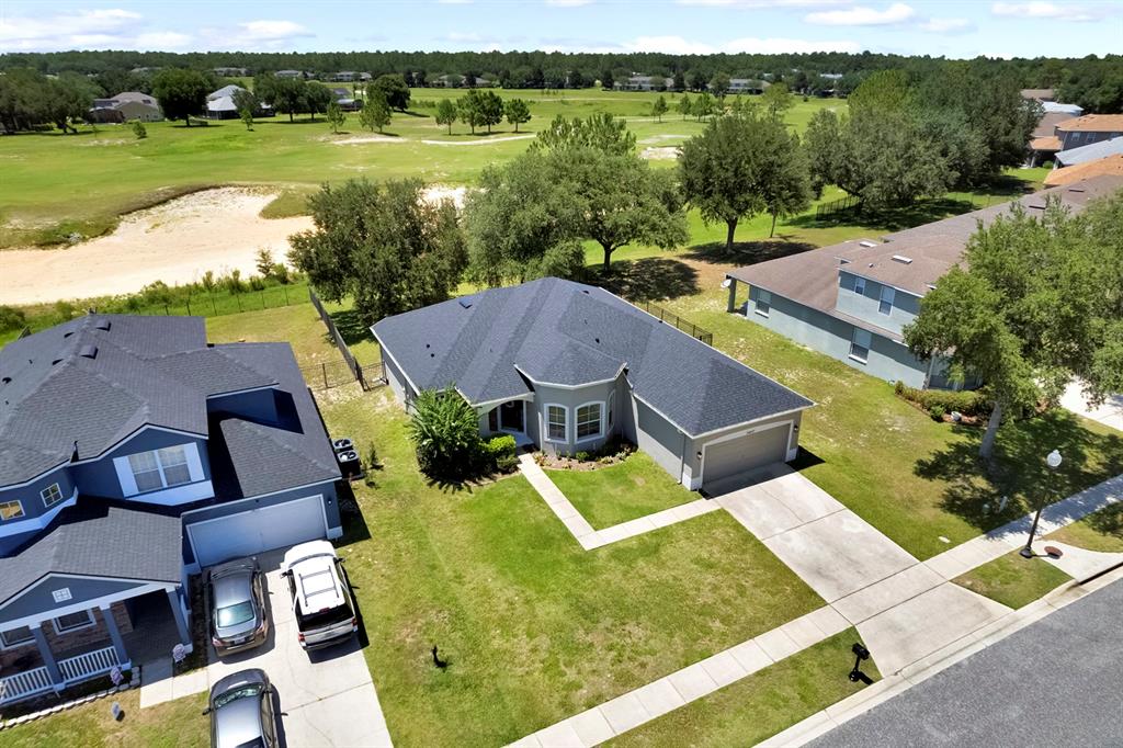 An aerial view shows a single-story suburban house with a gray roof and driveway — 34037 FORTUNADO STREET, SORRENTO, FL